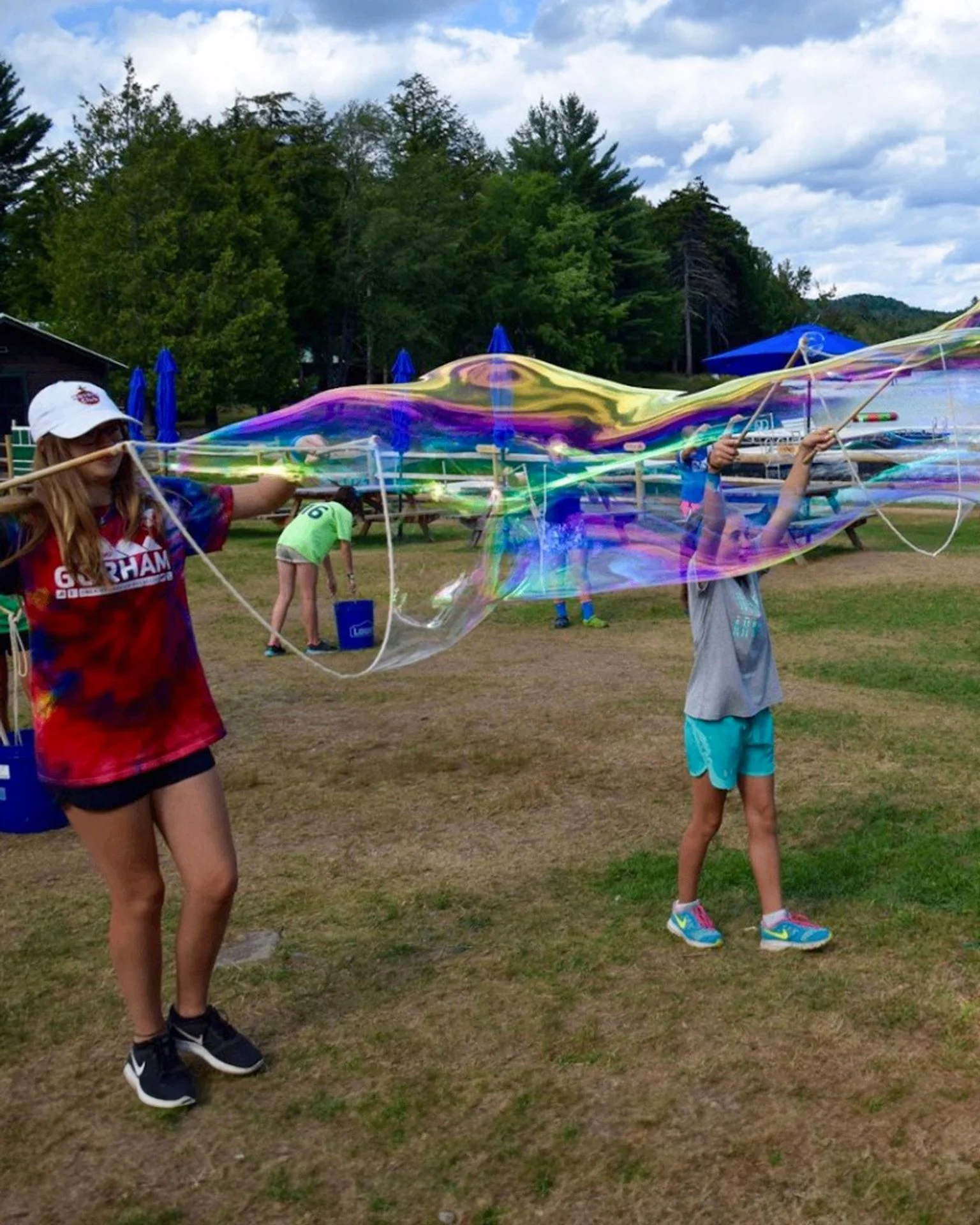 Children at camp using wooden bubble sticks to make a long giant bubble